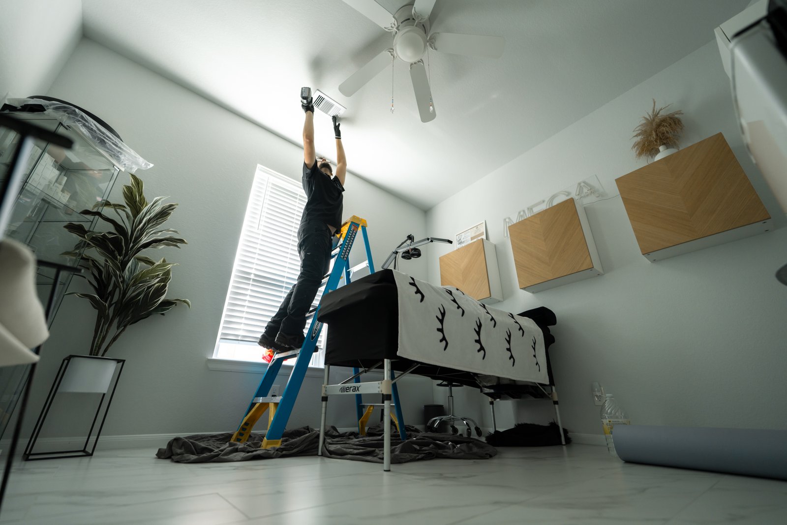 Technician on ladder cleaning ceiling vent inside Pasadena home