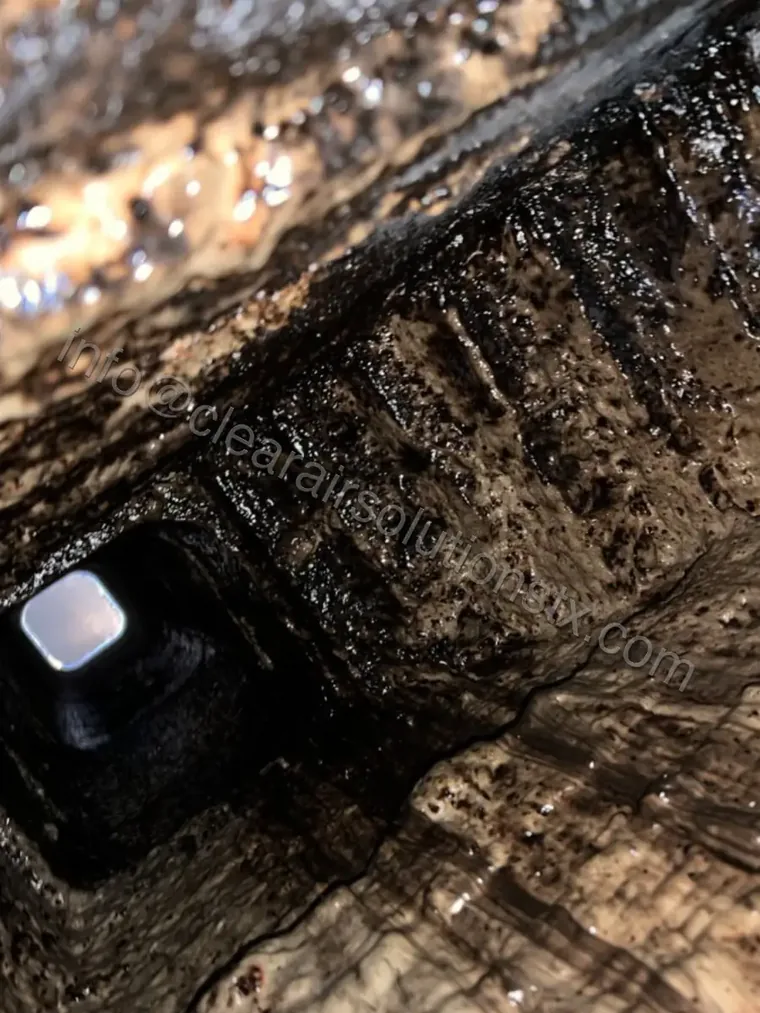 Glazed creosote buildup inside a chimney flue before removal